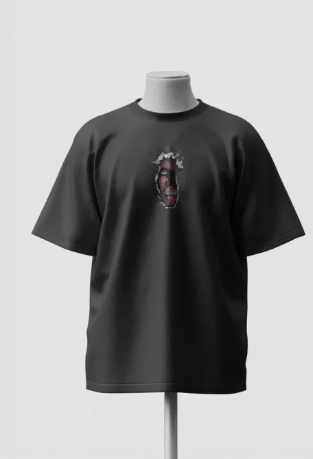 Small Colossal Titan face showing through a torn opening on the chest of a black oversized t-shirt